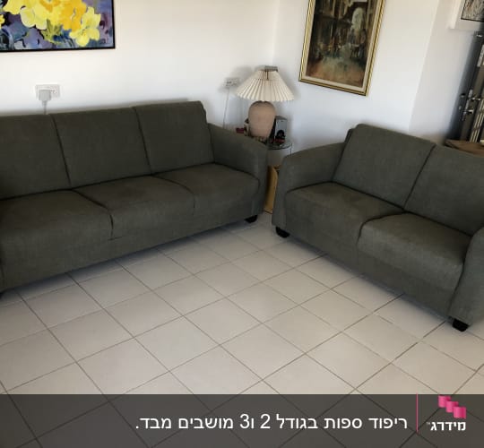 שתי ספות מרופדות בבד אפור כהה על רצפת אריחים לבנים